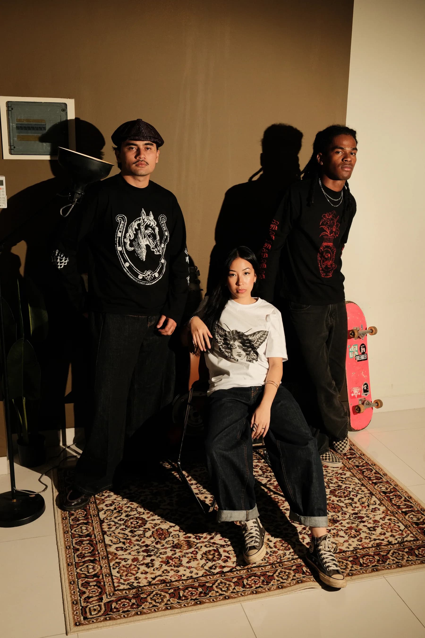 Three models wearing TOHO graphic pieces in a warmly lit interior.